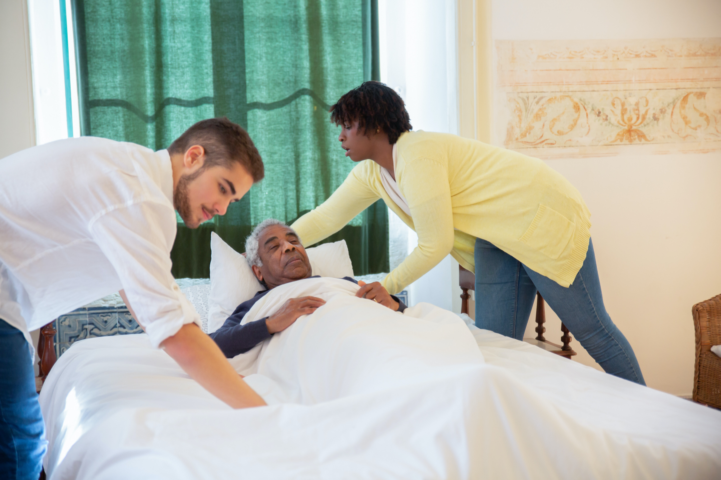 Image of two care assistants tucking a client into bed.