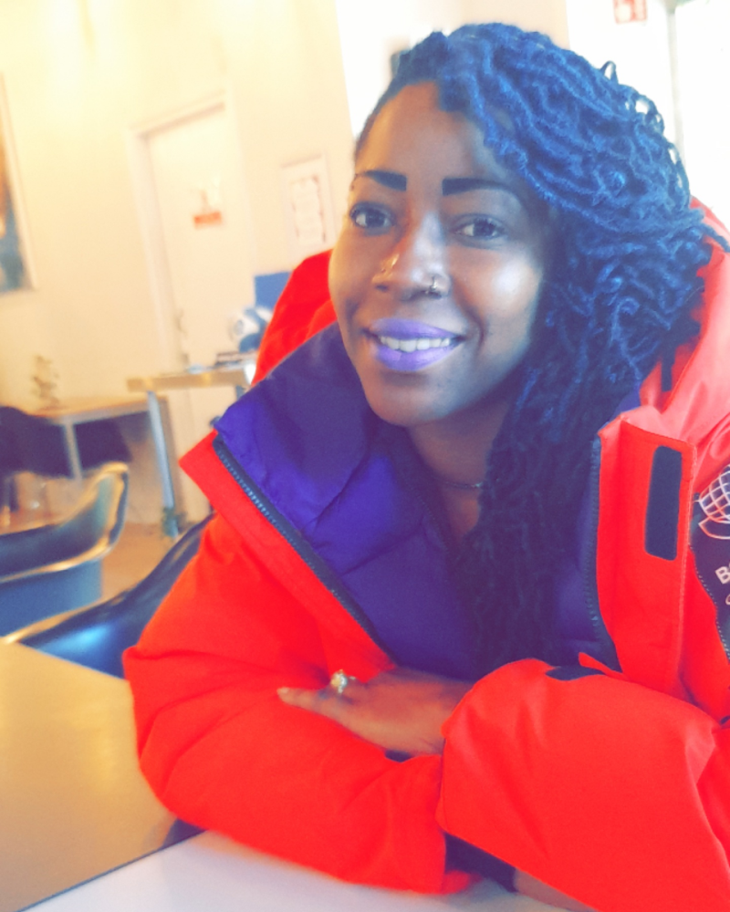 Black woman in red jacket smiling into the camera