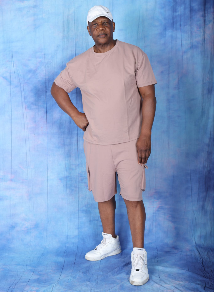 Black man wearing casual clothes smiling in the camera in front of a blue background