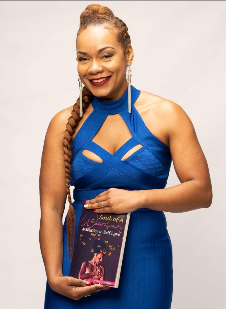 Black woman smiling in the camera while holding the book she wrote