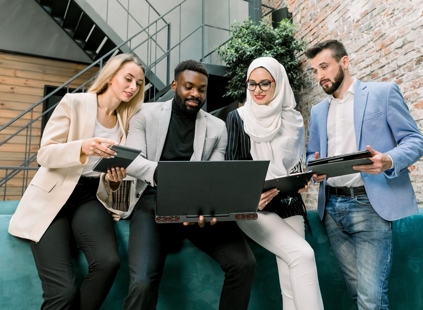 An image of 4 people looking at a laptop