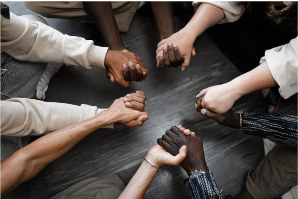 Diverse looking hands are holding each other over a table