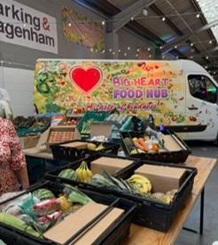 Fresh food is put out in boxes on a table in front of a colourfully painted van