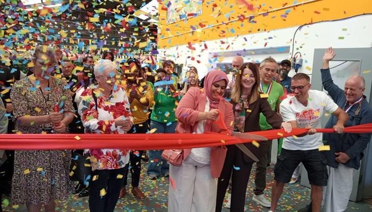 Councillors are cutting a red ribbon under a large amount of confetti