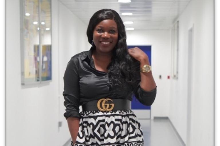Young black woman standing in a corridor smiling into the camera