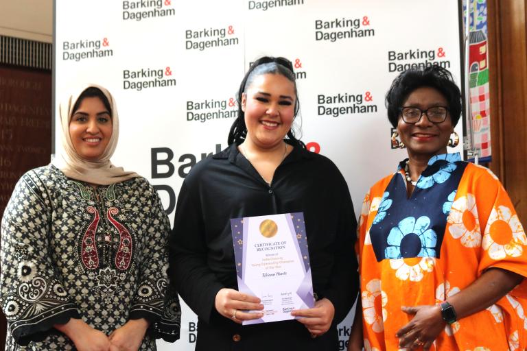 Rhiann Hunte is showing their winning certificate in the Town Hall with Cllr Ashraf and Cllr Bright