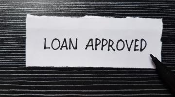 Loan approved words on a piece of paper with black background