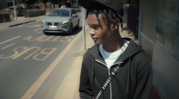 Young man standing at bus stop in Dagenham