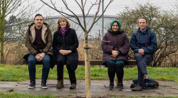 People sitting on a bench in front of a tree