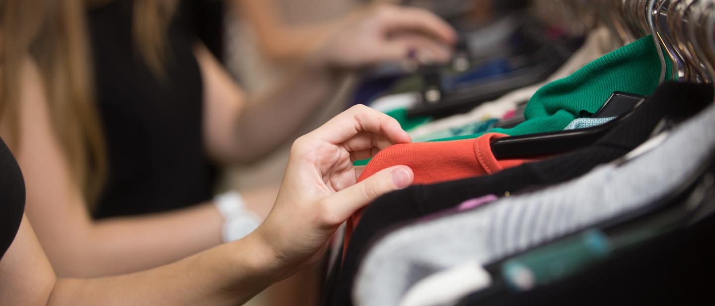 woman searching through clothes on a rack