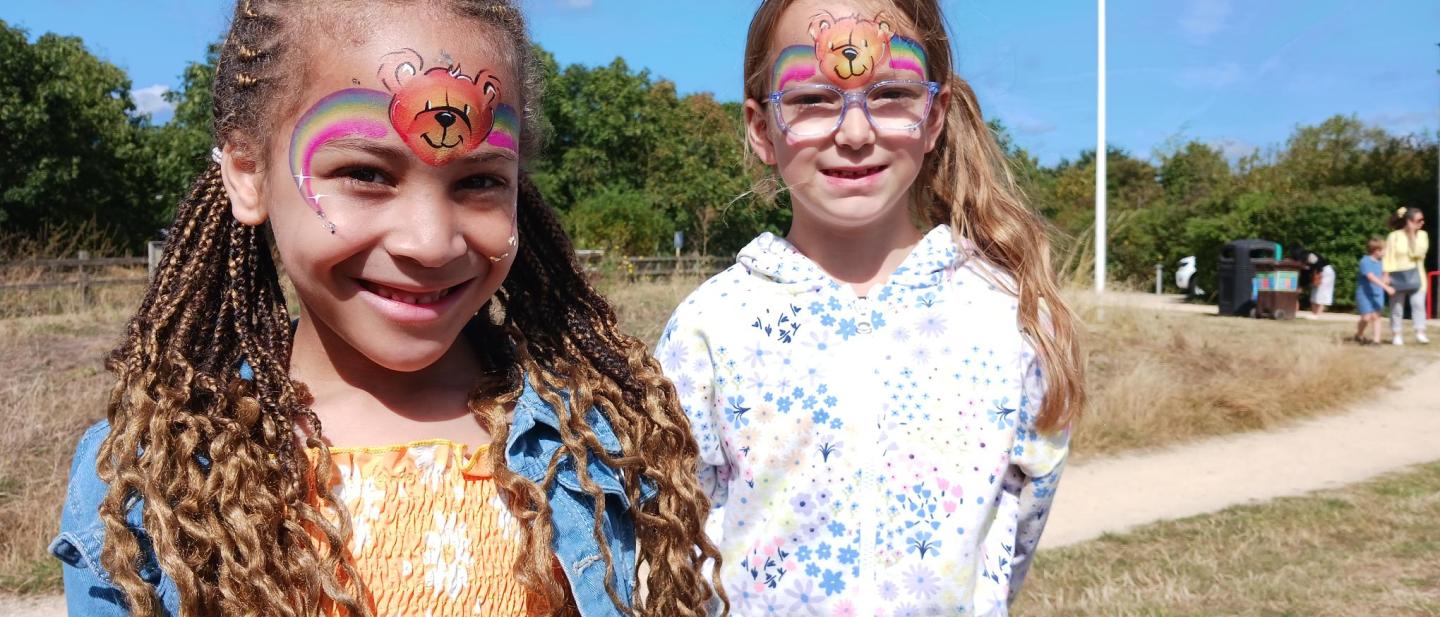 Two young girls with face paint are smiling to the camera