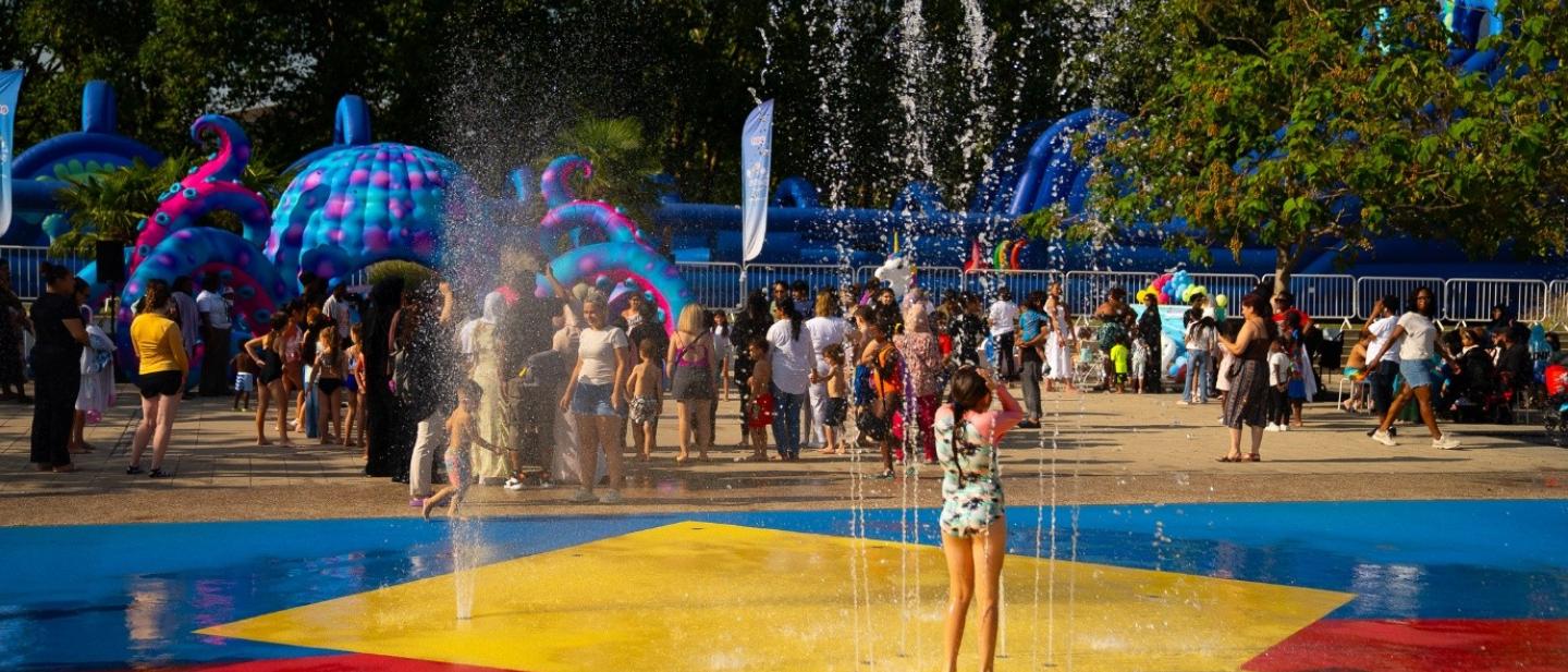 A young child is standing under water in a colourful waterpark pool
