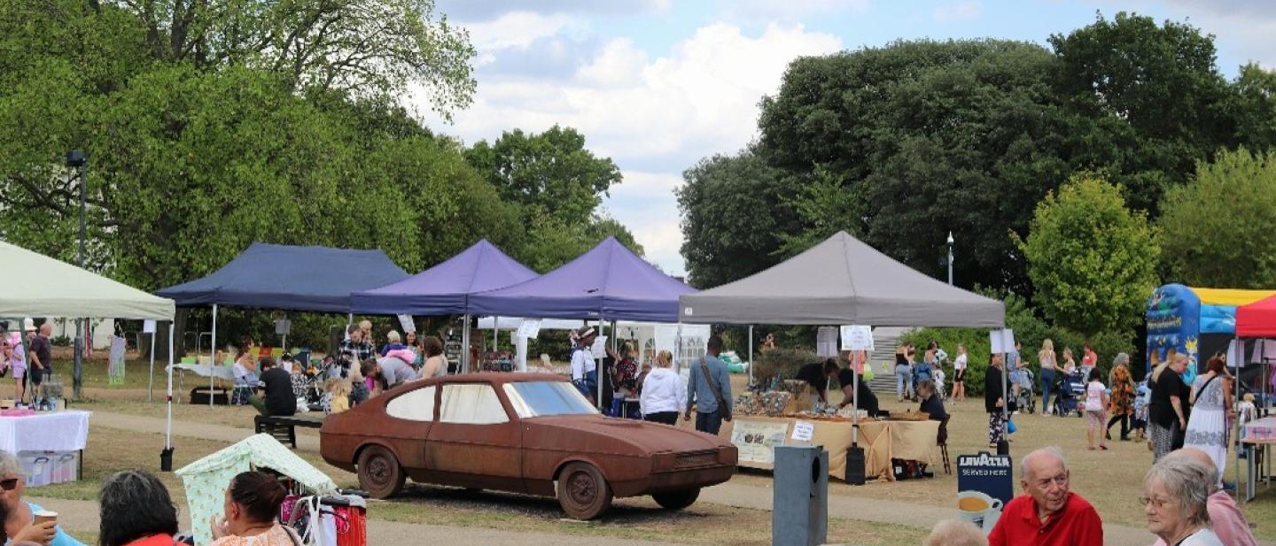 A picnic with tents and an old, rusty car in the middle