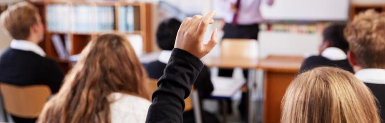 Pupil is holding hand up in a classroom