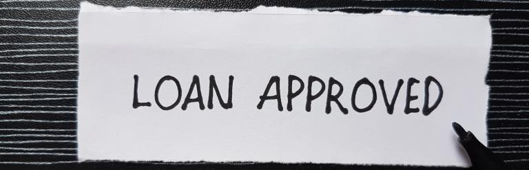 Loan approved words on a piece of paper with black background