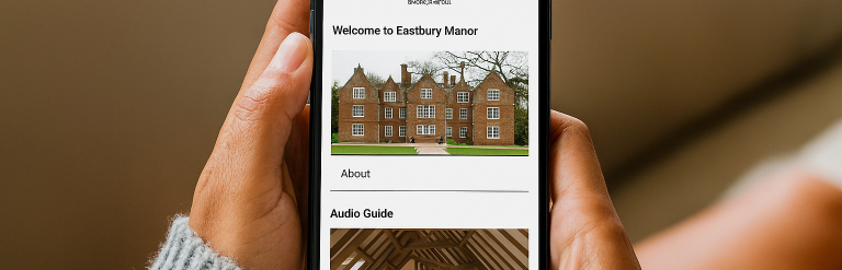 A photo of somebody holding a smartphone. Eastbury Manor House's website is on the screen with the text 'Welcome to Eastbury Manor' above an image of the house. Underneath the text says 'Audio guide'