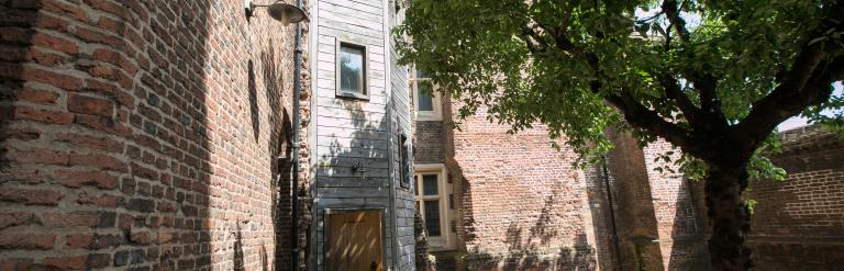 Wall and a side entrance of Eastbury Manor House with a tree in the foreground