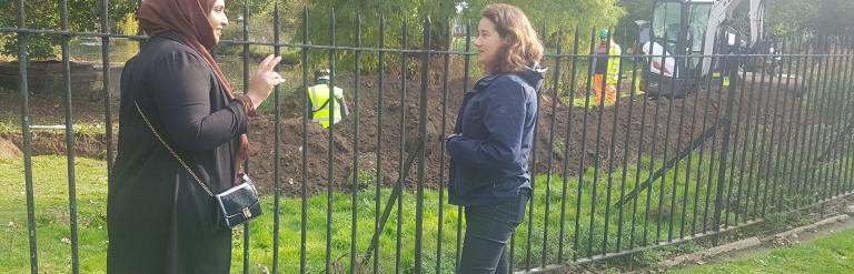 Two people standing in front of an archaeological dig