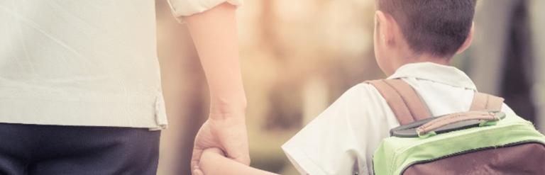 young child holding their parent's hand on their way to school 