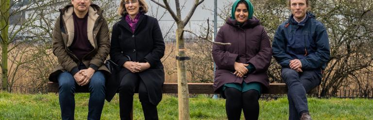 People sitting on a bench in front of a tree