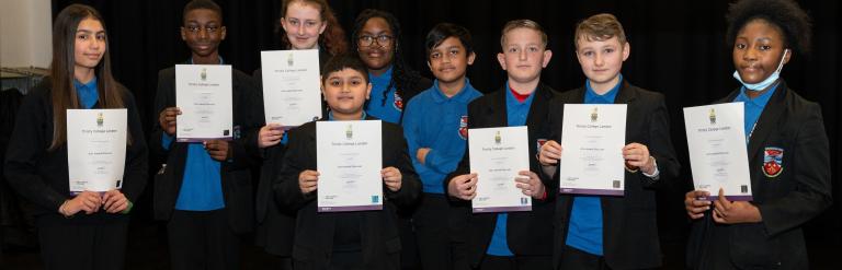 pupils on stage at dagenham park holding up arts award discover certificates