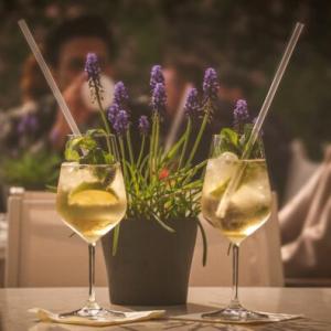 Image of two wine glasses on a table with flowers behind them