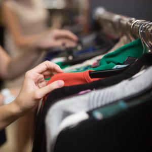 woman searching through clothes on a rack