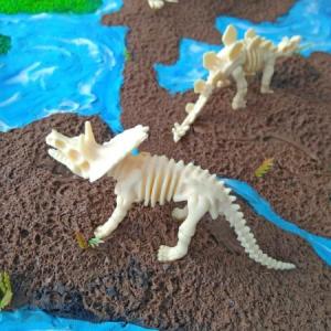 Image of two dinosaur skeleton toys on a landscape