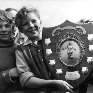young boy holding a big plague for winners