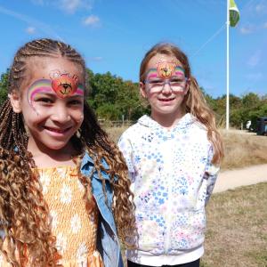 Two young girls with face paint are smiling to the camera