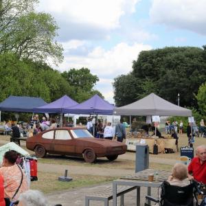 A picnic with tents and an old, rusty car in the middle